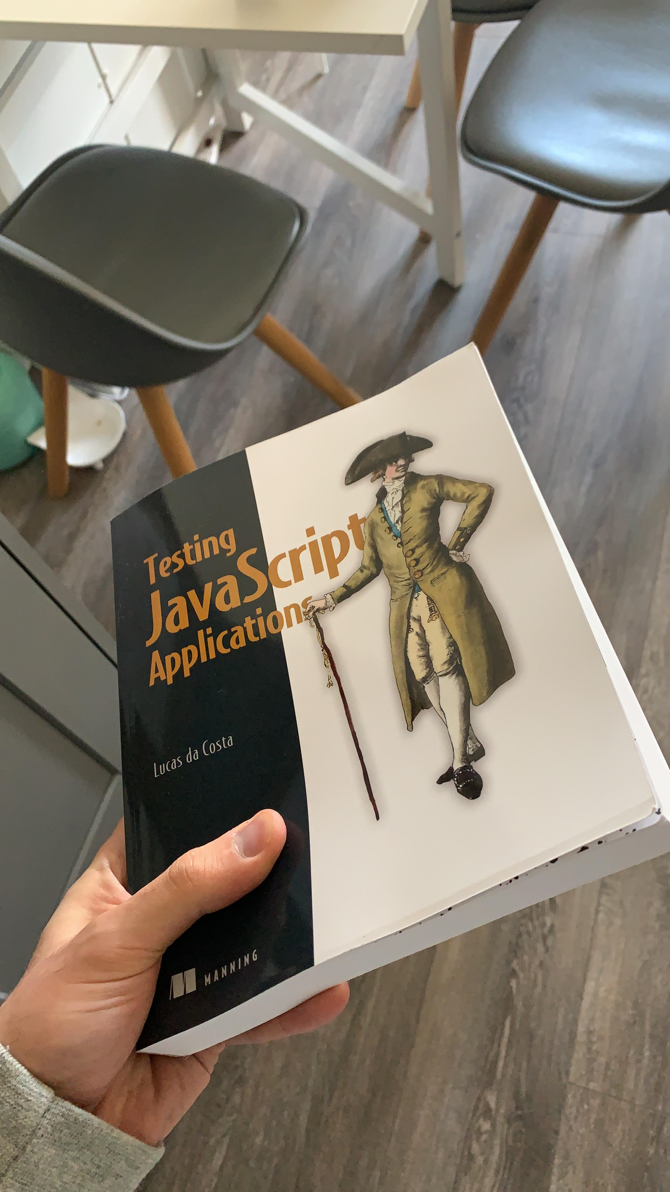 A picture of my hand holding the book I had written, called Testing JavaScript applications.