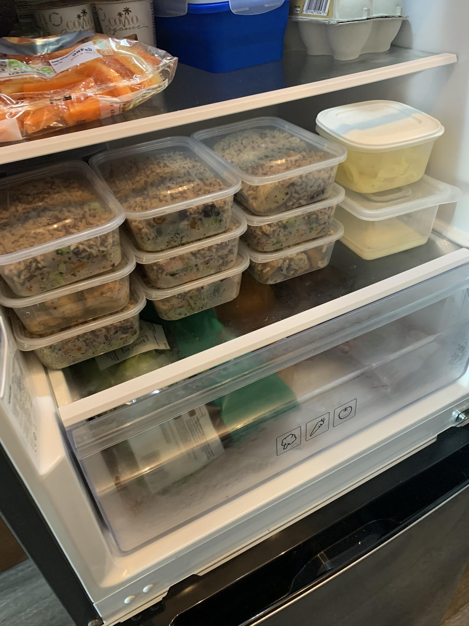 An open fridge with quite a few plastic containers full of food.